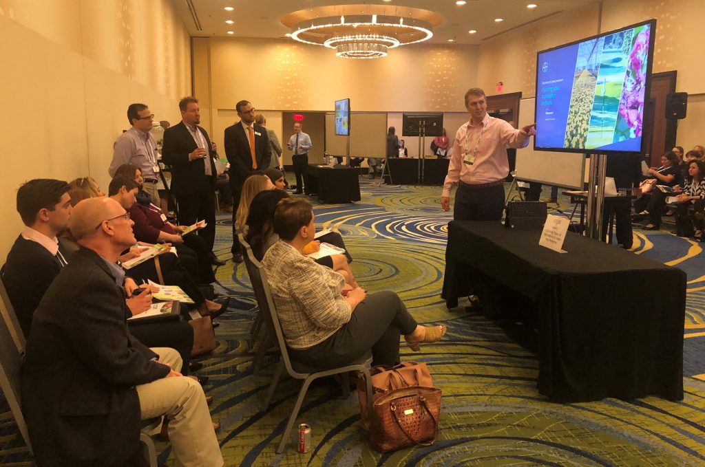 Man points at a screen as he presents to a group.